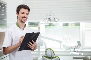 Attractive male dental doctor is working in his office