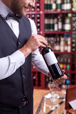 Cheerful young male waiter is working in liquor store