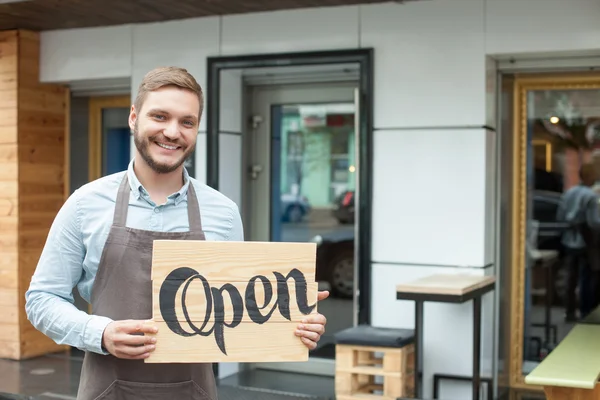 Bonito jovem barista está anunciando sua cafetaria — Fotografia de Stock