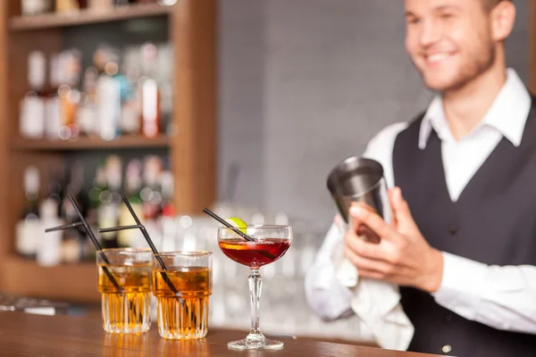 Attractive male bartender is shaking drink in pub — Stockfoto