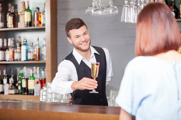 Cheerful male bartender is serving customer in bar — Stock fotografie