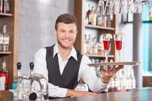 Atraente jovem barman está servindo clientes no bar — Fotografia de Stock