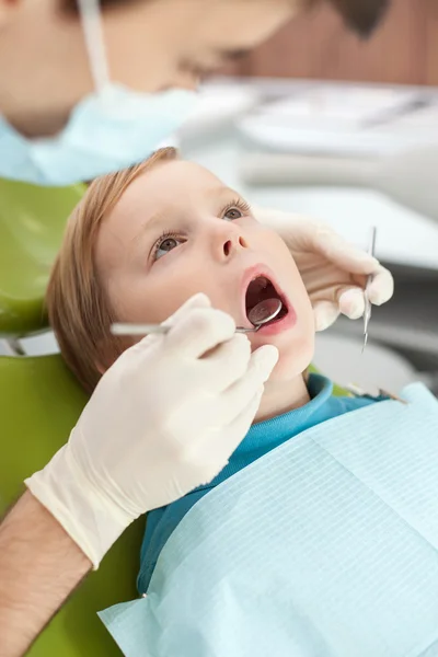 Cheerful young dentist is checking tooth of child — 스톡 사진