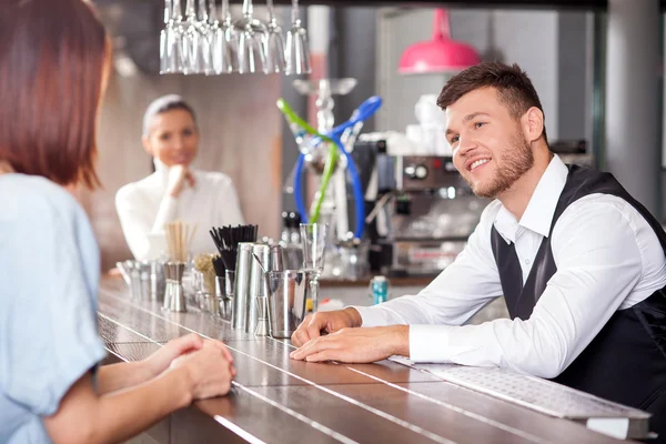 Привлекательный молодой бармен флиртует с клиентами-женщинами — стоковое фото