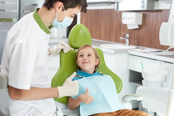 Joven dentista alegre está viendo a un niño pequeño —  Fotos de Stock
