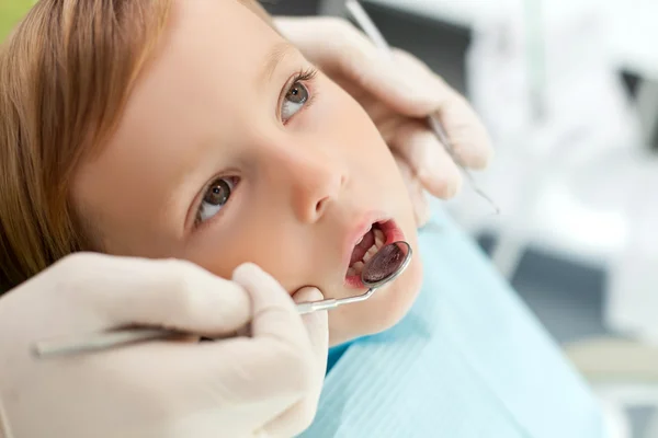 Profesional joven dentista está tratando a su pequeño paciente —  Fotos de Stock