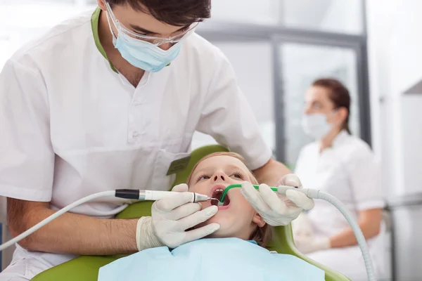 Attractive male dental doctor is treating his patient — Stock Photo, Image