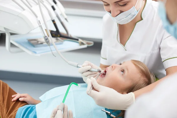 Skillful female dentist is treating small patient — 스톡 사진