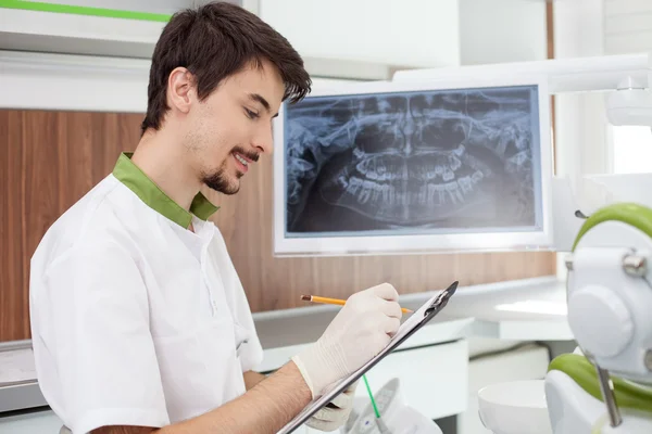 Attraktiver männlicher Zahnarzt analysiert Zähne im Büro — Stockfoto