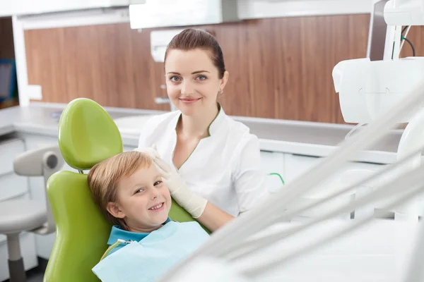 Alegre dentista femenina está trabajando con un niño pequeño — Foto de Stock