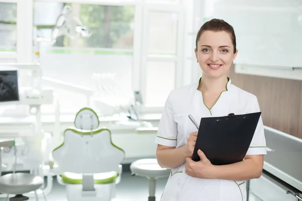 Cheerful female dentist is making notes in lab — Stock fotografie