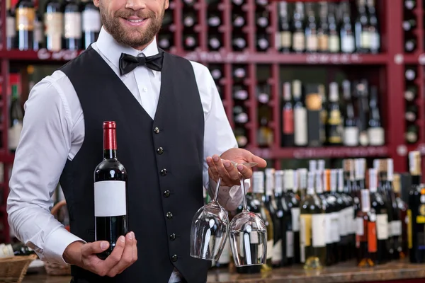 Cheerful young waiter is carrying alcohol drink in cellar — ストック写真