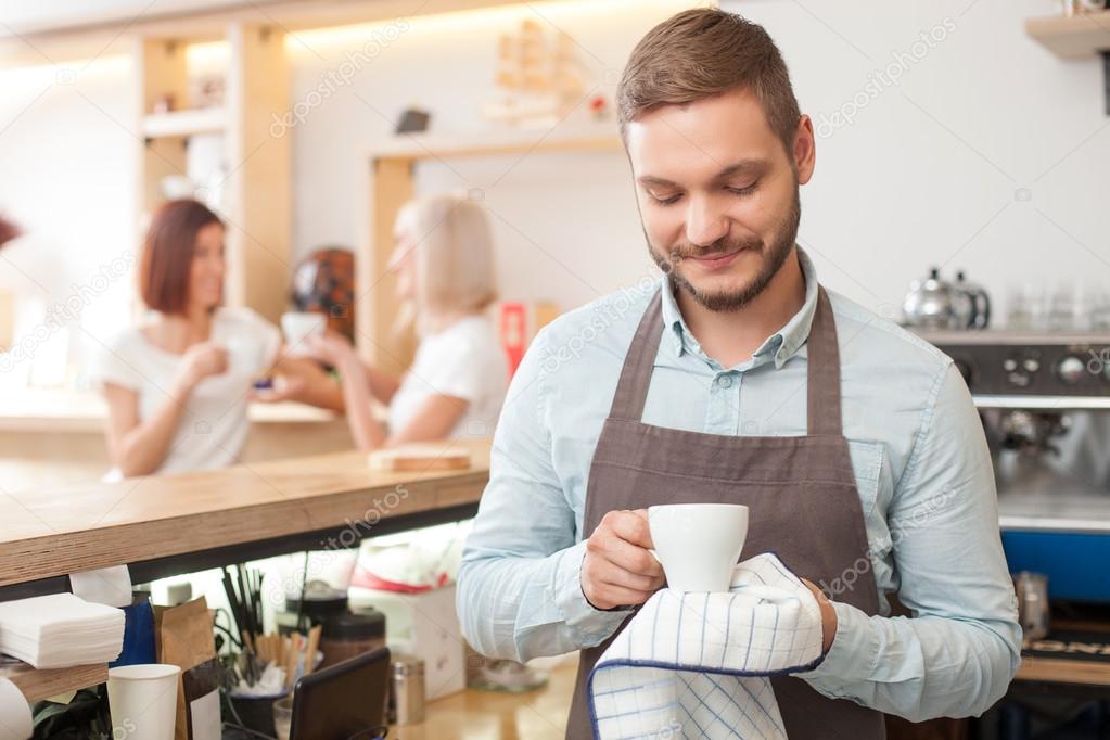 Attractive male worker is serving customers in cafeteria