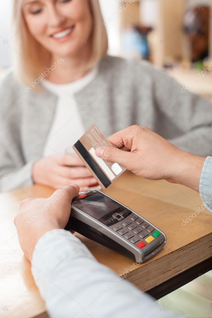 Cheerful male cafe worker is receiving payment