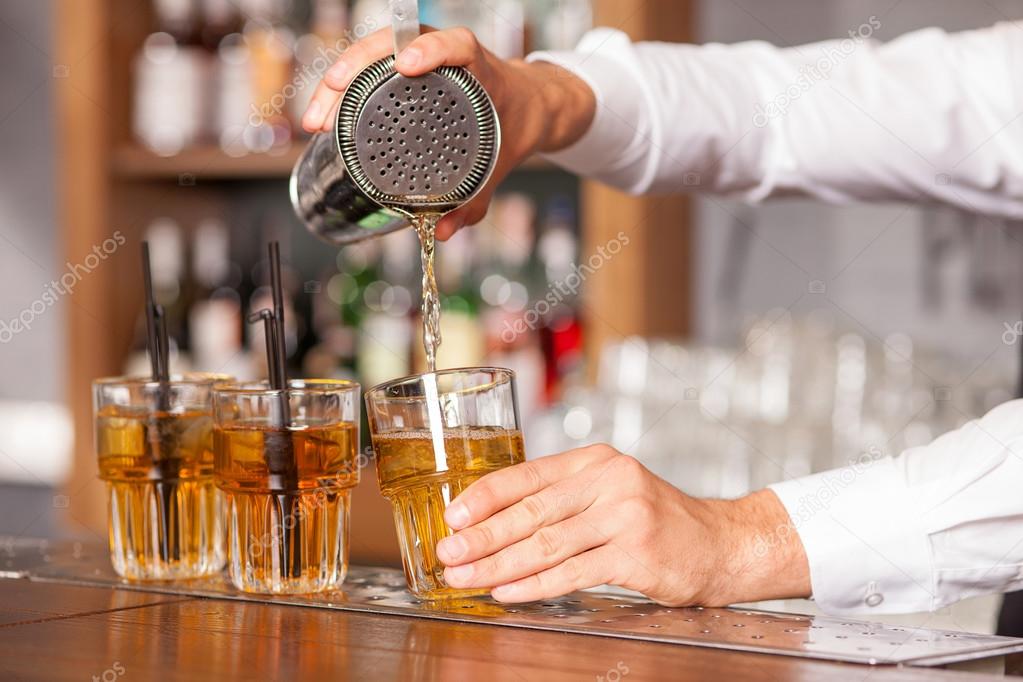 Professional male bartender is mixing drink in pub