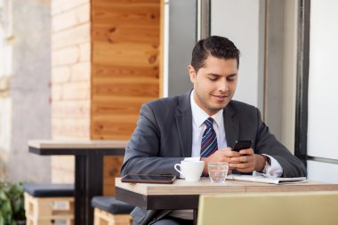 Handsome man with suit is using telephone in cafe