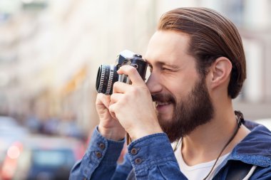 Attractive bearded man is making photos of city