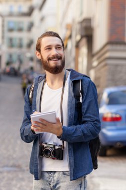 Cheerful bearded man is making his journey in town