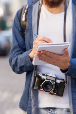 Cheerful bearded male tourist with pan and note-book