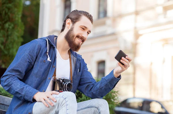 Cheerful young hipster is using technology during journey — Stockfoto