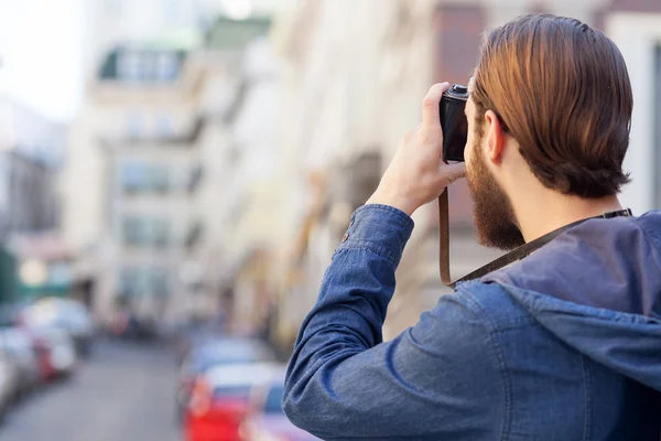 Cheerful bearded photographer is making photos of town — ストック写真