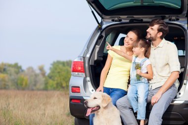 Cute friendly family is resting in forest near vehicle