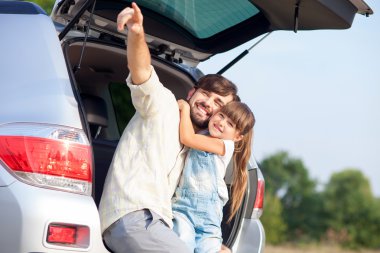 Cheerful father with child in forest near vehicle