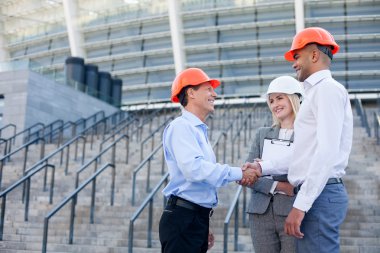 Skillful three architects are greeting each other with handshake
