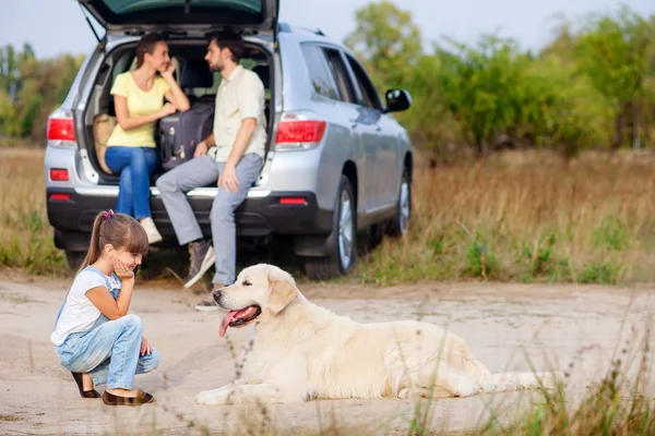 Cute family and pet are resting near vehicle outdoors — Zdjęcie stockowe