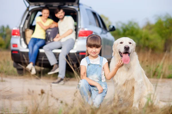 Pais alegres e criança com cachorro perto do veículo — Fotografia de Stock