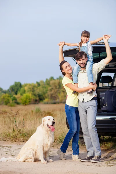 Pretty parents and child with puppy near vehicle — Zdjęcie stockowe