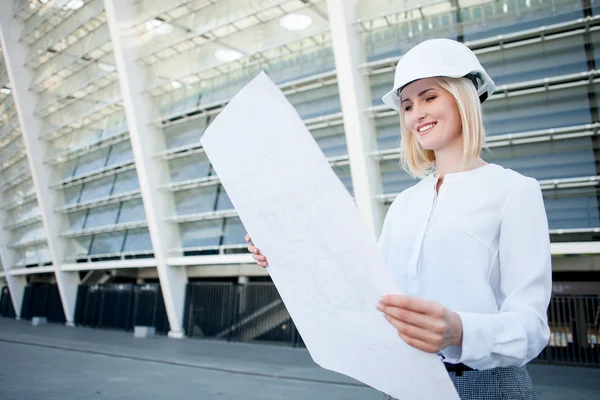 Attractive young female engineer is watching sketch of building — 스톡 사진