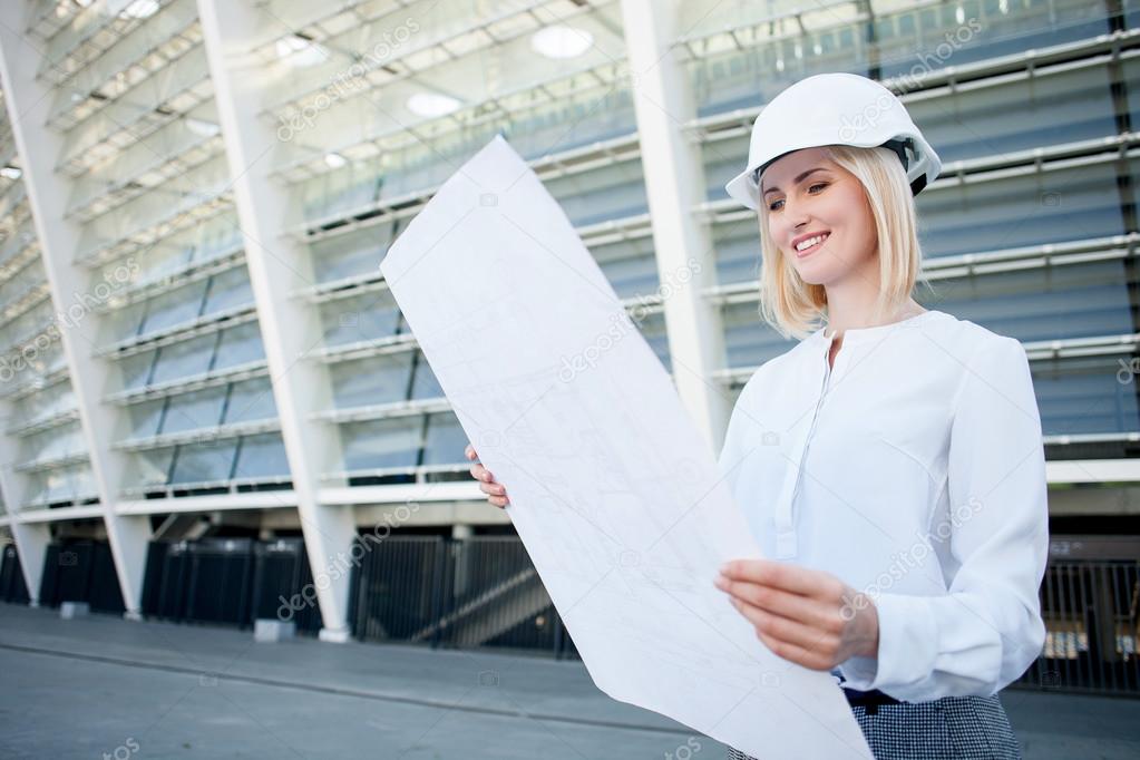 Attractive young female engineer is watching sketch of building