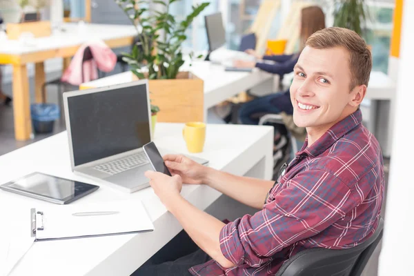 Fröhlicher Manager arbeitet mit Telefon und Notebook — Stockfoto