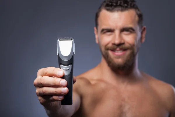 Cheerful bearded guy is showing new shaver — Stock fotografie