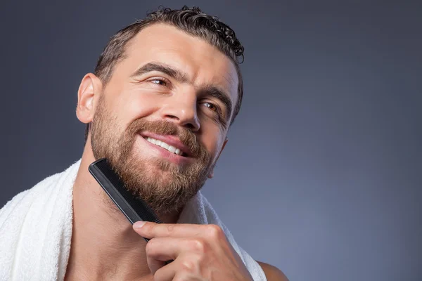 Cheerful young bearded guy with comb and smile — Stockfoto