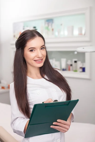 Cheerful female expert beautician is making notes — ストック写真