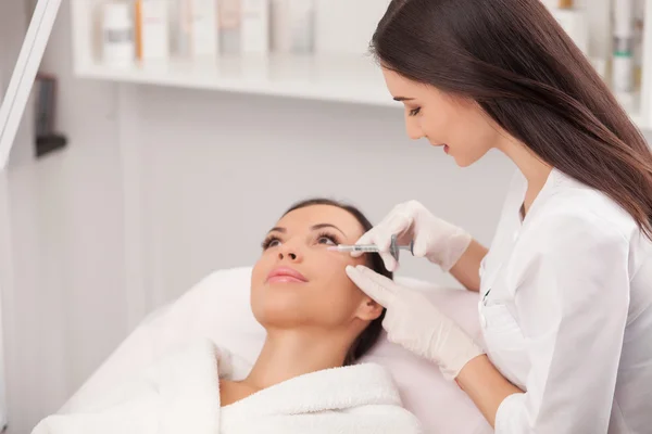 Jovem cosmetologista alegre está fazendo procedimento botox — Fotografia de Stock