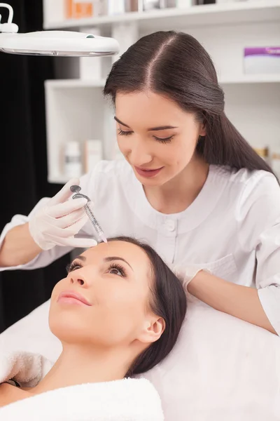 Весела жінка-експерт косметолог обслуговує свого пацієнта — стокове фото