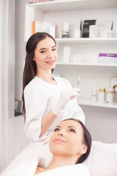 Cosmetologist feminino atraente está servindo seu cliente — Fotografia de Stock