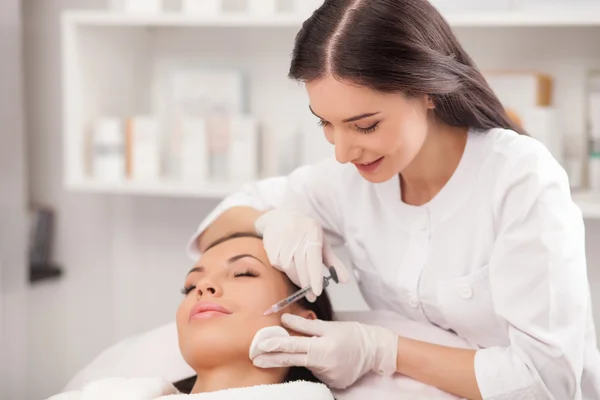 Attractive expert beautician is injecting female face — Stock Photo, Image