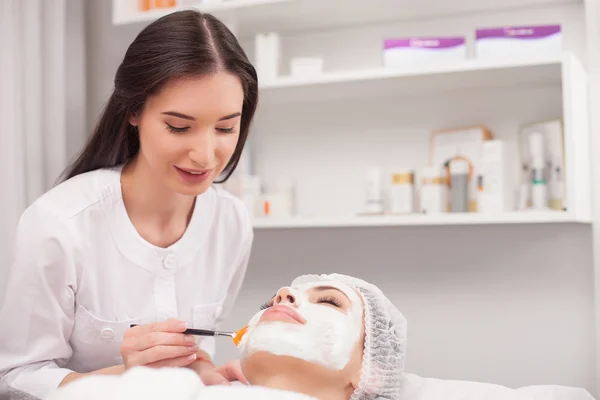 Cheerful expert beautician is serving her customer — Stock Photo, Image