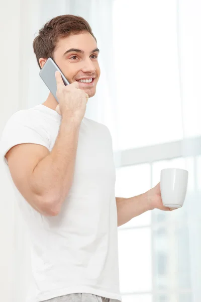 Cheerful young guy is enjoying hot drink — Stock Photo, Image