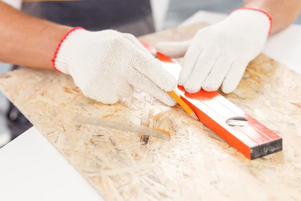 Fröhlicher Bauarbeiter misst Holzplattform — Stockfoto