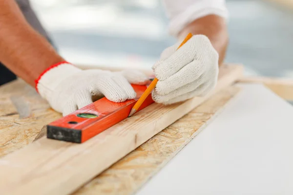 Professioneller männlicher Bauarbeiter misst Holzplattform — Stockfoto