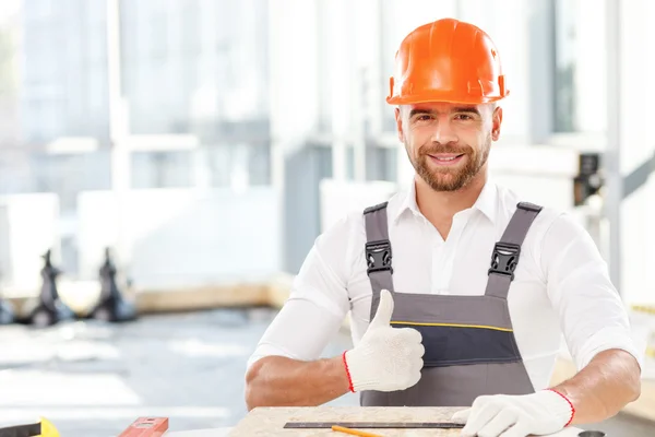 Construtor masculino atraente está trabalhando com material de madeira — Fotografia de Stock