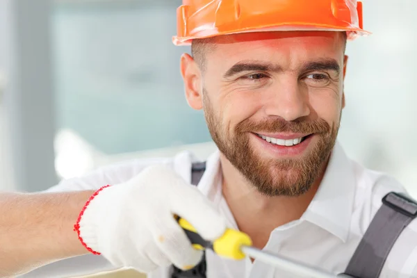 Handsome young builder is installing furniture in house — Stock Photo, Image