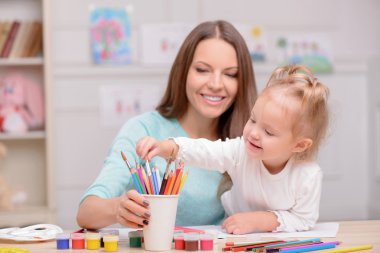 Pretty woman is teaching her child to draw