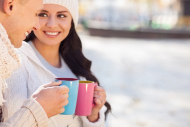 Pretty lovers are enjoying hot drink in the nature
