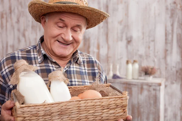 Alegre viejo trabajador masculino con productos lácteos — Foto de Stock